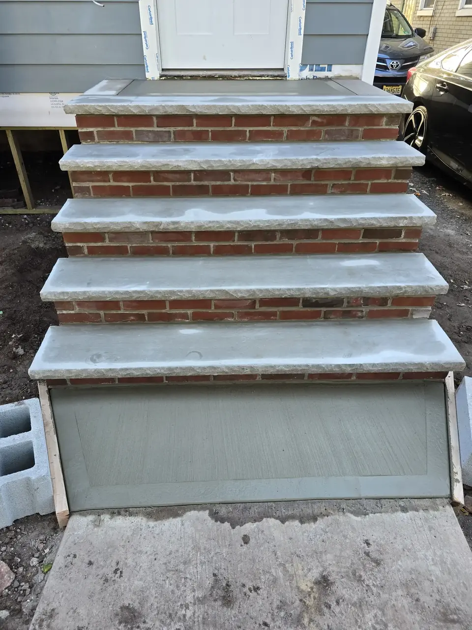 New brick steps with stone treads and a formed concrete landing